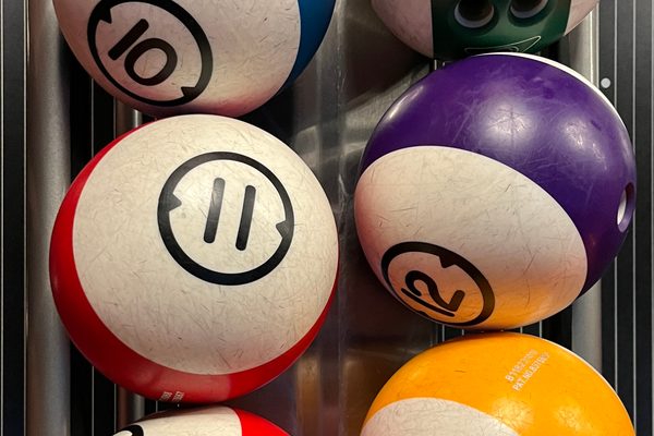 House balls with finger holes on a rack; entry Brunswick bowling balls such as the TZone look similar