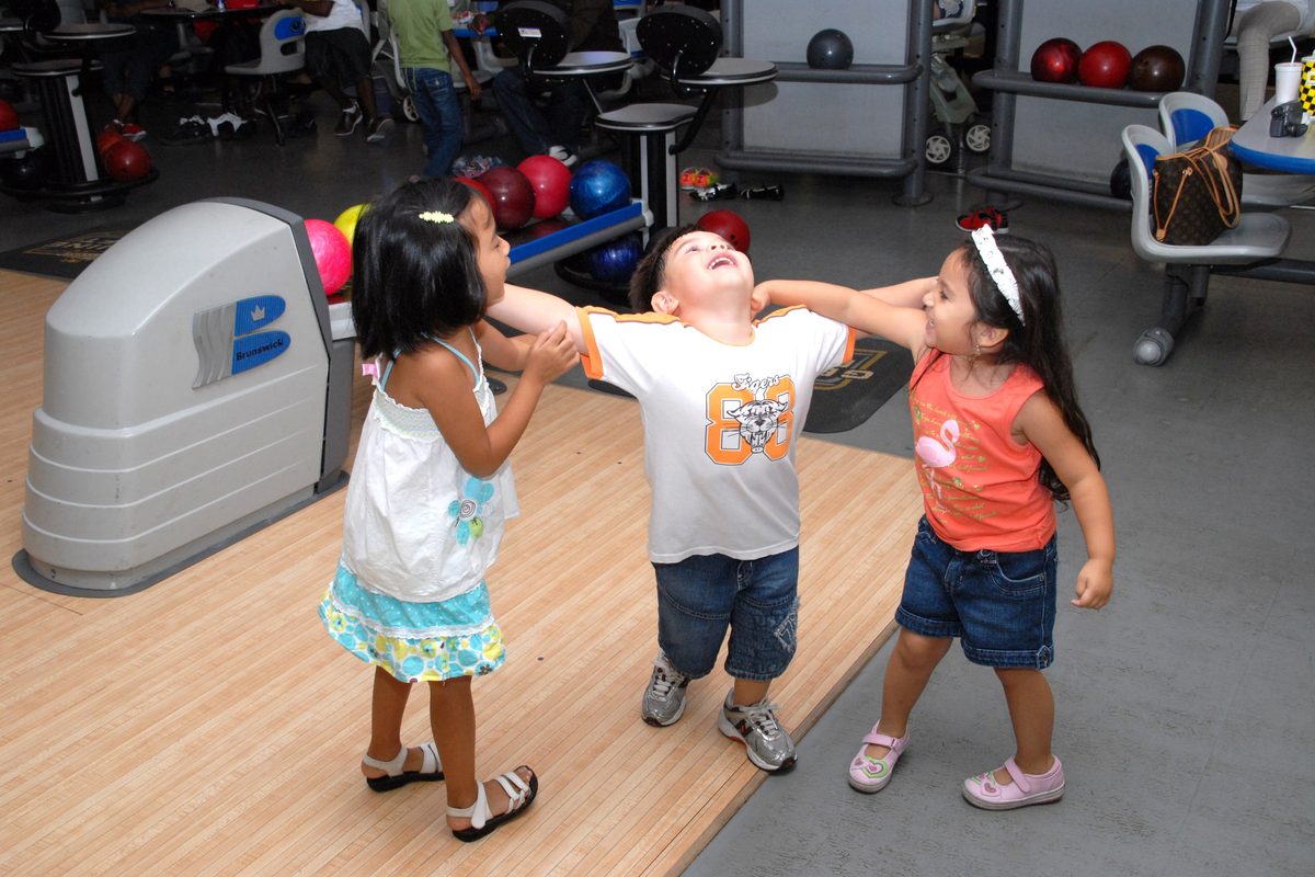Young children having fun at a bowling alley during a family day, the kind of scene at kids bowling parties
