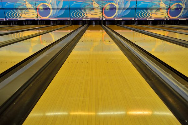 Polished wooden lane seen from the approach, the surface where bowling oil patterns are applied